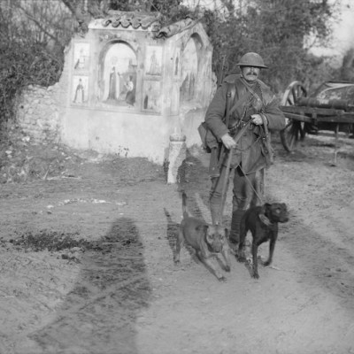 Soldier from the Royal Engineers with two messenger dogs and a roadside shrine (December 1917), Ernest Brooks. Courtesy: Imperial War Museum