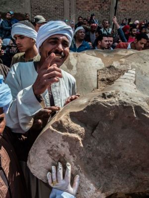 Egyptian workers pose next to an excavated statue, recently discovered by a team of German-Egyptian archeologists, in Cairo's Mattarya district on March 13, 2017.