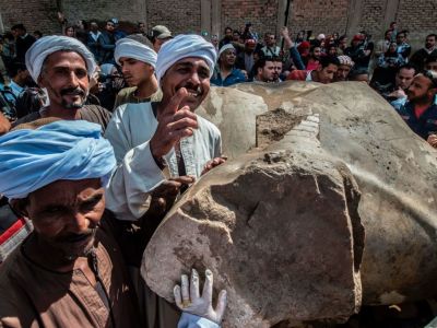 Egyptian workers pose next to an excavated statue, recently discovered by a team of German-Egyptian archeologists, in Cairo's Mattarya district on March 13, 2017.