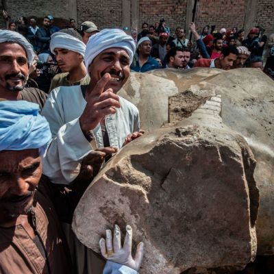 Egyptian workers pose next to an excavated statue, recently discovered by a team of German-Egyptian archeologists, in Cairo's Mattarya district on March 13, 2017.