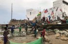 Fishermen in front of Cape Coast Castle, Ghana, with a staircase on the left leading up to a ‘Door of No Return’.