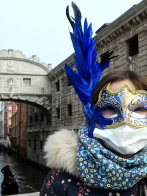 A tourist in Venice on 24 February 2020, wearing a protective face-mask and a Carnival mask.
