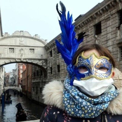 A tourist in Venice on 24 February 2020, wearing a protective face-mask and a Carnival mask.
