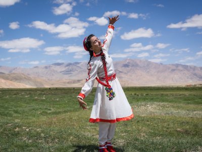 A girl in traditional Tajik dress dances at the opening of a new tourism centre in Bulunkul, Tajikistan (2019), Christopher Wilton-Steer.