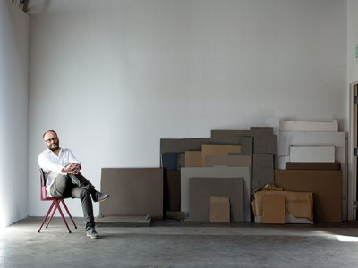 portrait of a man sitting on a chair in a warehouse space