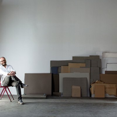 portrait of a man sitting on a chair in a warehouse space