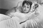 Actress Olivia de Havilland lying on a bed