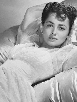 Actress Olivia de Havilland lying on a bed