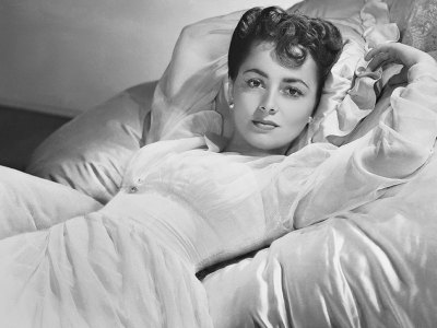 Actress Olivia de Havilland lying on a bed