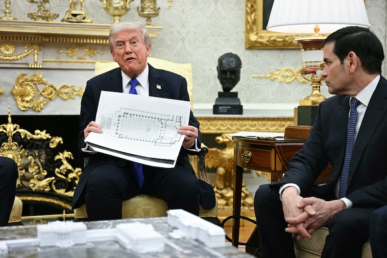 Donald Trump holding up a plan of the White House ballroom in the Oval Office