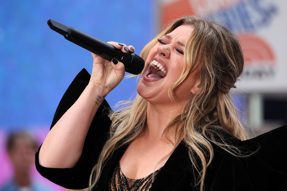 Singer Kelly Clarkson singing vigorously into a microphone
