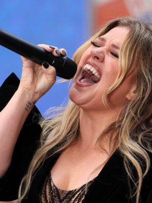 Singer Kelly Clarkson singing vigorously into a microphone