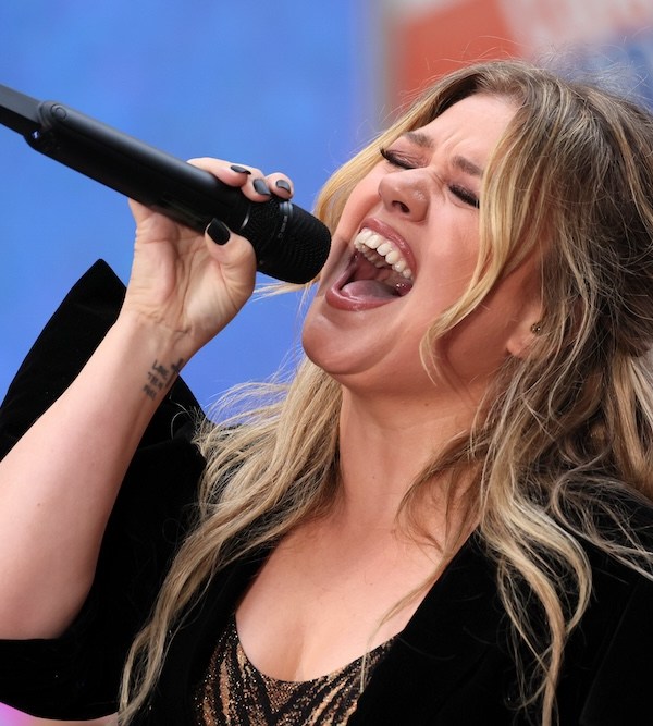 Singer Kelly Clarkson singing vigorously into a microphone